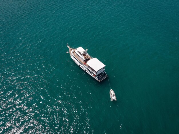 Aerial view of the big motor vessel with lifeboat, white sides and wooden deck; boats  concept.