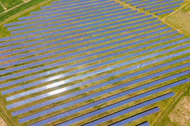 Aerial view of big sustainable electric power plant with many rows of solar photovoltaic panels for producing clean ecological electrical energy. Renewable electricity with zero emission concept.