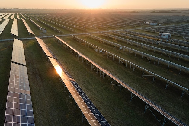 日没時にクリーンな電気エネルギーを生成するための太陽光発電パネルの多くの列を備えた大きな持続可能な発電所の航空写真ゼロ排出コンセプトの再生可能エネルギー