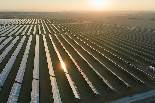 日没時にクリーンな電気エネルギーを生成するための太陽光発電パネルの多くの列を備えた大きな持続可能な発電所の航空写真ゼロ排出コンセプトの再生可能エネルギー