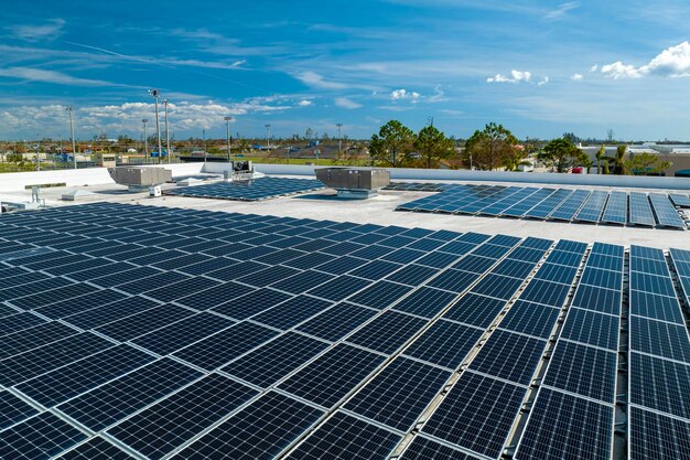 Aerial view of blue photovoltaic solar panels mounted on industrial building roof for producing clean ecological electricity Production of renewable energy concept