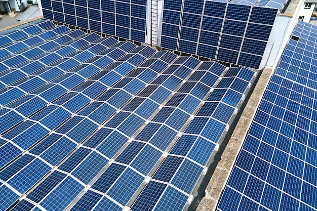 Aerial view of blue photovoltaic solar panels mounted on industrial building roof for producing green ecological electricity. Production of sustainable energy concept.