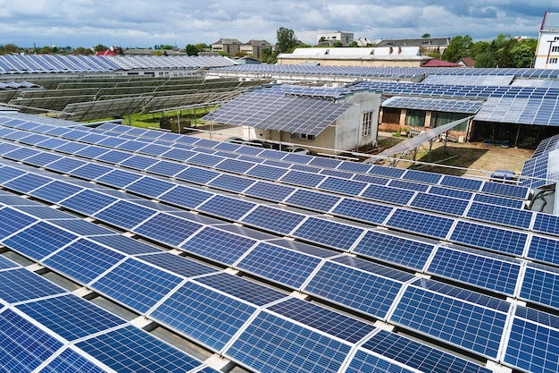 Вид с воздуха на синие фотоэлектрические солнечные панели, установленные на крыше промышленного здания для производства экологически чистой электроэнергии. Производство концепции устойчивой энергетики.