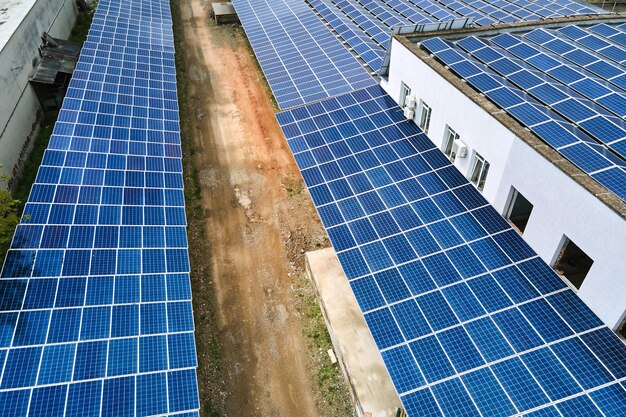 Aerial view of blue photovoltaic solar panels mounted on industrial building roof for producing green ecological electricity Production of sustainable energy concept