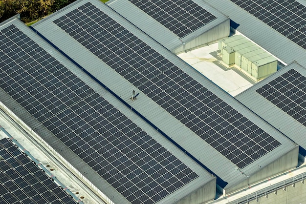 Aerial view of blue photovoltaic solar panels mounted on industrial building roof for producing green ecological electricity Production of sustainable energy concept