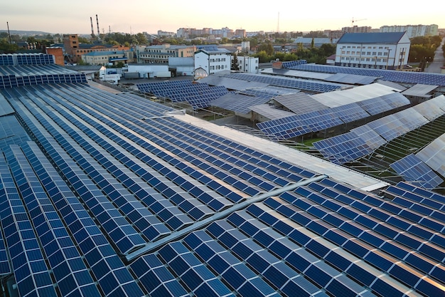 Aerial view of blue photovoltaic solar panels mounted on industrial building roof for producing green ecological electricity Production of sustainable energy concept