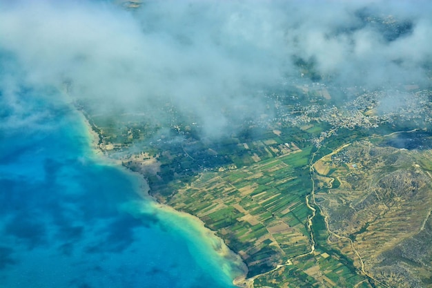 Photo aerial view of the blue sea and green land from the window of an airplane flying over haiti