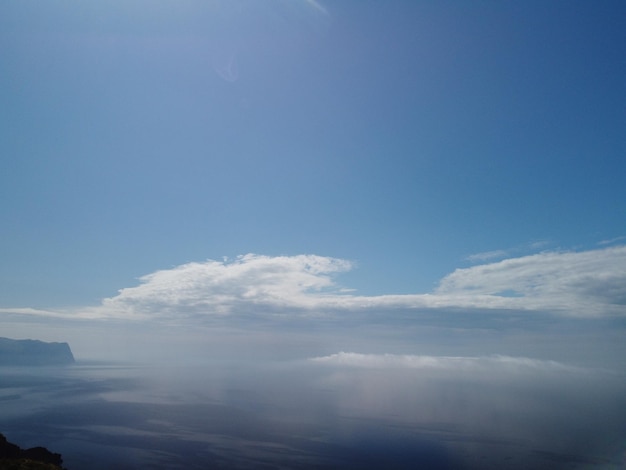 空撮青空太陽と穏やかな海の霧ドローンは霧とふわふわの雲の上を飛ぶ抽象