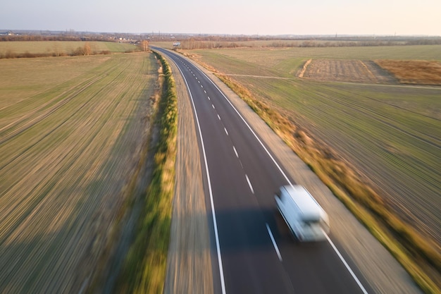 高速道路の運搬用品を運転しているぼやけた高速移動貨物バンの航空写真。配送輸送とロジスティクスの概念