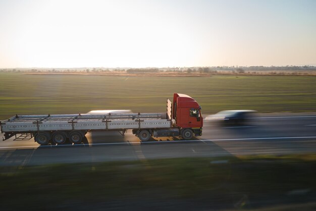 Photo aerial view of blurred fast moving semitruck with cargo trailer driving on highway hauling goods in evening delivery transportation and logistics concept