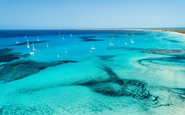 Aerial view of boats and luxury yachts in transparent sea at sunny bright day summer seascape tropical landscape with lagoon boats azure water sandy beach blue sky top view from drone travel