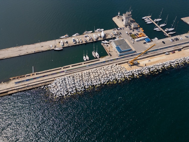 Photo aerial view of breakwater construction crane on a pile of boulders in the sea