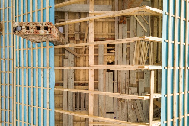 Aerial view of a brick house with wooden roof frame under construction.