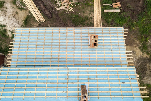 Aerial view of a brick house with wooden roof frame under construction.