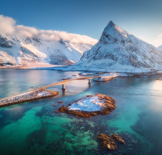 Aerial view of bridge over the sea and snowy mountains in Lofoten Islands, Norway. Fredvang bridges at sunset in winter.