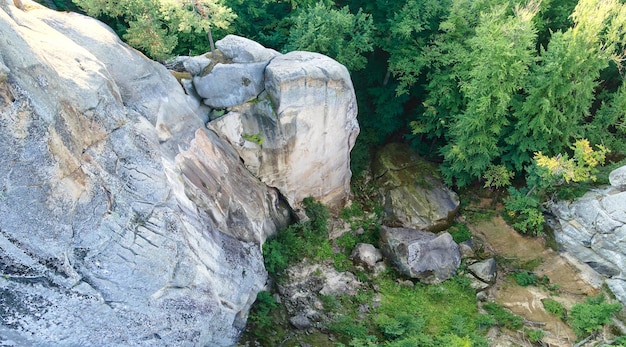 Aerial view of bright landscape with green forest trees and big rocky boulders between dense woods in summer Beautiful scenery of wild woodland