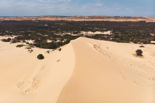 Aerial view of brown winding sand dunes with fourwheel car in Muine Vietnam