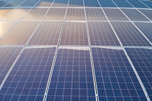 Aerial view building roof with rows of blue solar photovoltaic panels for producing clean ecological electric energy. Renewable electricity with zero emission concept.