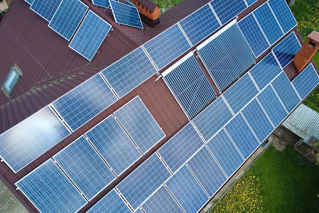 クリーンな生態系電気エネルギーを生成するための青い太陽電池パネルの列を備えた空中写真の建物の屋根ゼロエミッションコンセプトの再生可能エネルギー