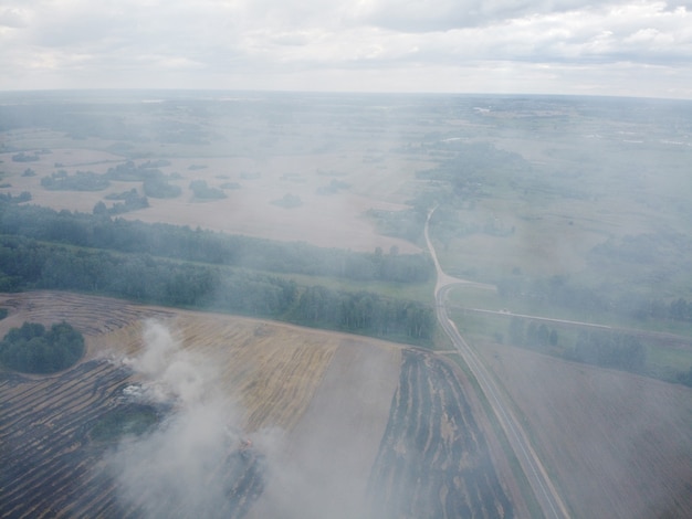 Aerial view of burning field with smoke in farm land