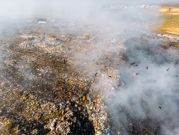 Photo aerial view of burning trash piles in landfill