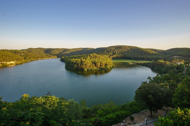 Aerial view of a calm lake surrounded by hills and trees