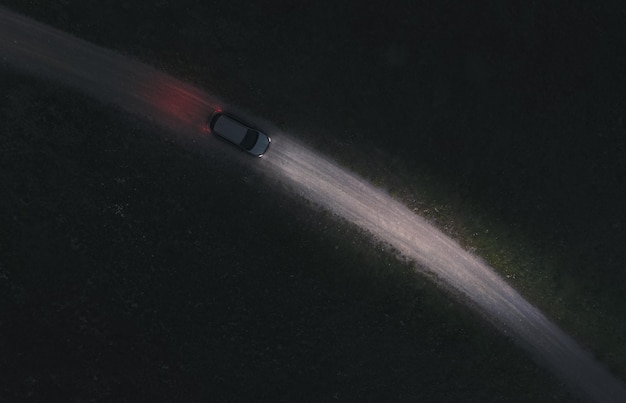 Aerial view of a car driving on a dirt country road at night