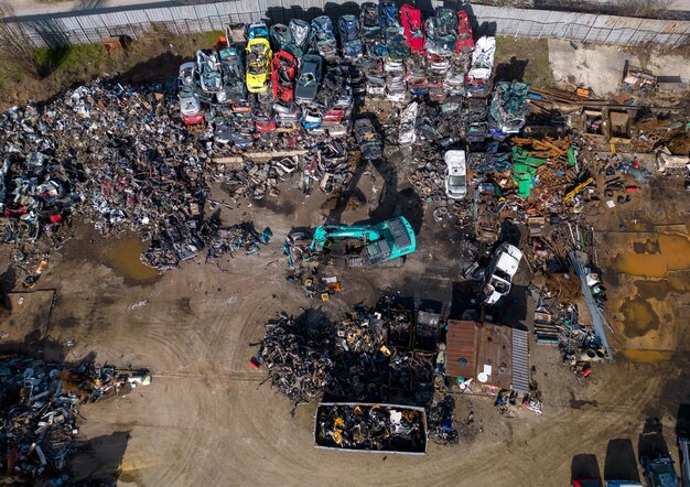 Aerial view of a car dump where a machine is seen separating old cars into scrap