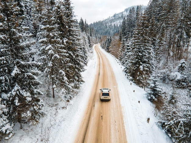 Аэрофотоснимок автомобиля на заснеженной дороге в зимний сезон в горах