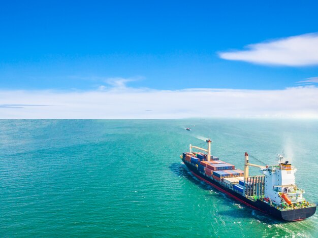 Вид с воздуха на грузовые суда, которые ходят посреди моря, перевозят контейнер в порт. Импорт, экспорт и доставка бизнес логистики и перевозки международных судов