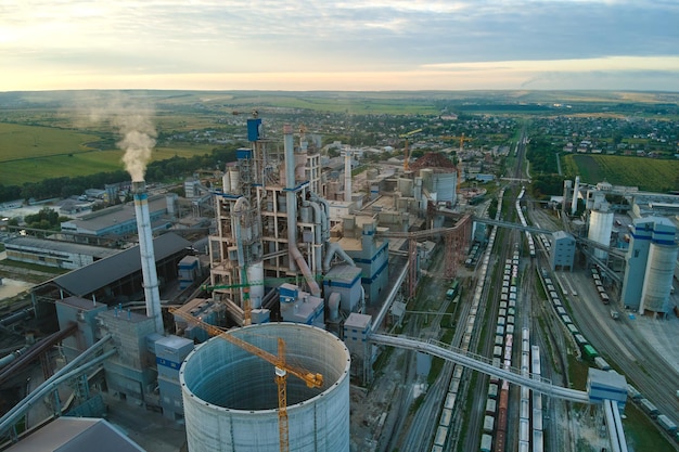 Aerial view of cement factory under construction with high concrete plant structure and tower cranes at industrial production area. Manufacture and global industry concept.