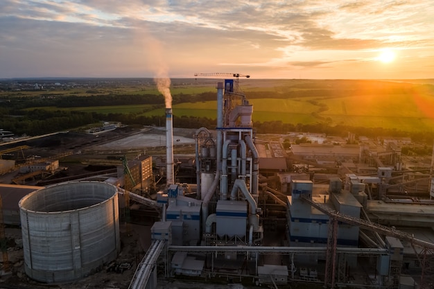 Aerial view of cement factory tower with high concrete plant structure at industrial production area. Manufacturing and global industry concept.