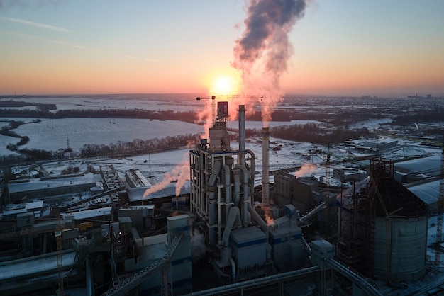 Aerial view of cement factory tower with high concrete plant structure at industrial production area at sunset manufacturing and global industry concept