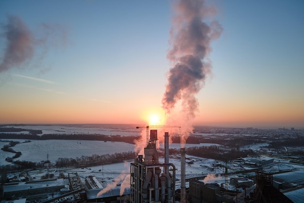 Aerial view of cement factory with high concrete plant structure and tower crane at industrial production area in evening Manufacture and global industry concept