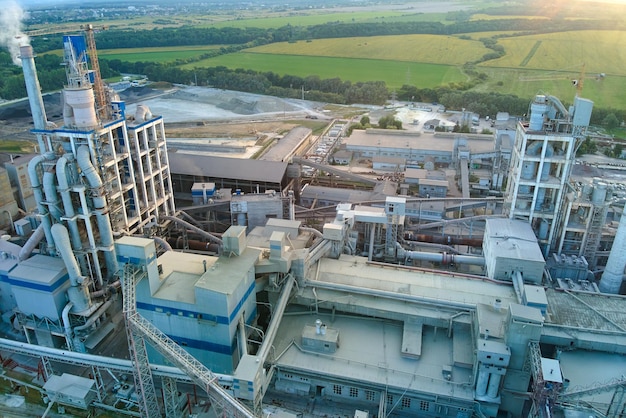 Aerial view of cement factory with high concrete plant structure and tower crane at industrial production site. Manufacture and global industry concept.