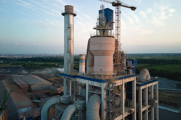 산업 생산 현장 제조 및 글로벌 산업 개념에서 높은 콘크리트 플랜트 구조와 타워 크레인이 있는 시멘트 공장의 항공 보기