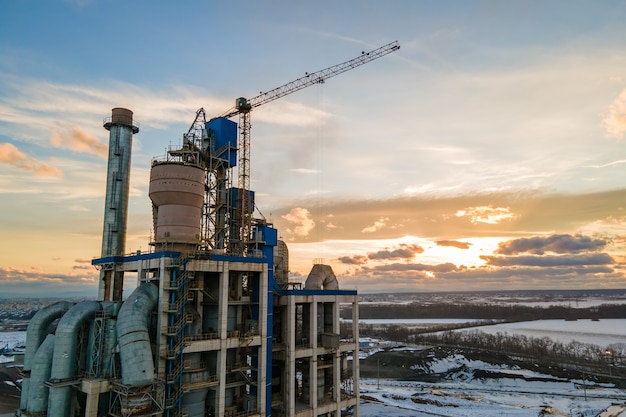 산업 생산 지역에 높은 공장 구조와 타워 크레인이 있는 시멘트 공장의 공중 전망.