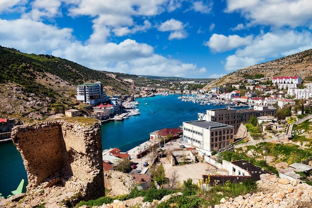 Aerial view of city Balaklava and bay with ships and embankment. Beautiful urban landscape of tourist spot. Backgrounds for site or large-resolution wallpaper. Concept of nature, tourism and adventure