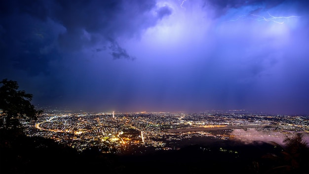 Photo aerial view city night from the view point on top of mountain in raining storm clouds with lightning chiang mai thailand