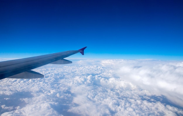 飛行機の窓からの雲の青い空と飛行機の翼の空撮