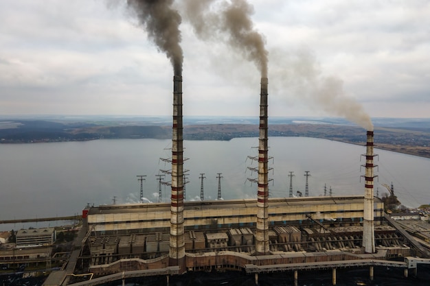 Aerial view of coal power plant high pipes with black smoke moving up polluting atmosphere.