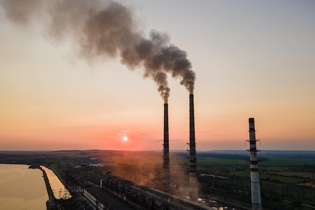 Aerial view of coal power plant high pipes with black smoke moving upwards polluting atmosphere at sunset Production of electrical energy with fossil fuel concept