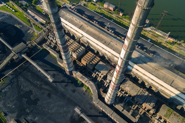 Aerial view of coal power plant high pipes with black smokestack polluting atmosphere. Electricity production with fossil fuel concept.