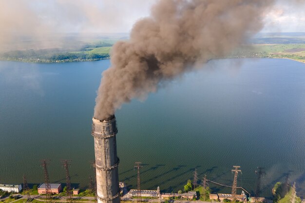 Aerial view of coal power plant high pipes with black smokestack polluting atmosphere. Electricity production with fossil fuel concept.