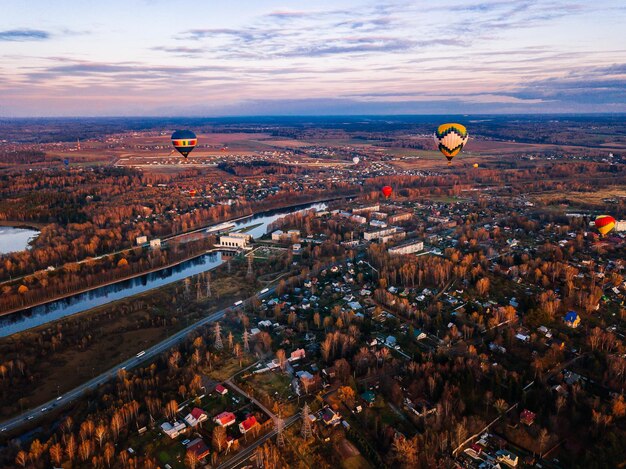 Aerial view of colorful hot air balloon is flying at sunset over the town in autumn fall season