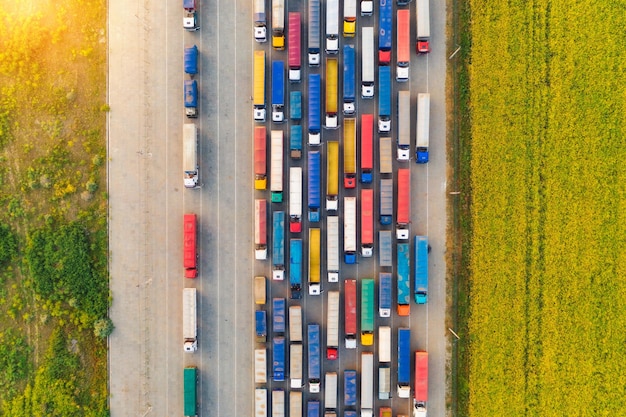 Aerial view of colorful trucks in terminal at sunset in summer Top view of logistic center Heavy industry Transportation Cargo transport shipping International trucking View from drone of truck