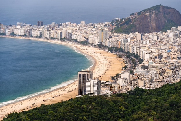 建物の海と風景のあるコパカバーナビーチの航空写真全長に沿った巨大な丘ブラジルのリオデジャネイロ市の広大さを背景に