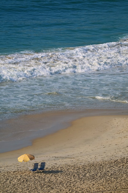 Foto veduta aerea della spiaggia di copacabana con un paio di sedie a sdraio e ombrellone