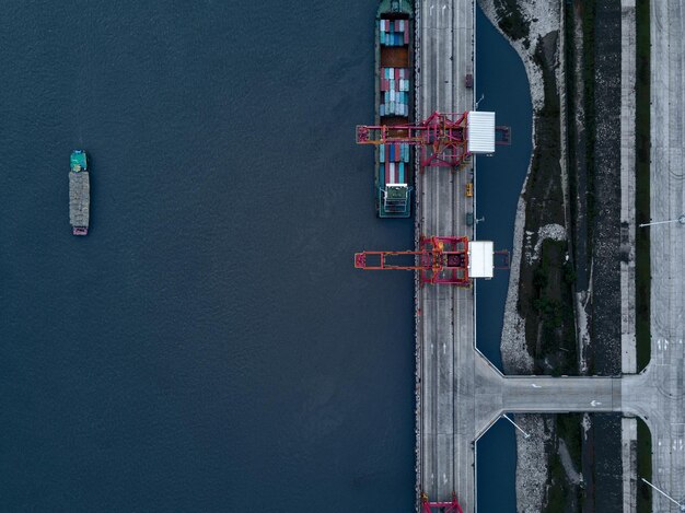 Photo aerial view of cranes on bridge by cargo ship over sea