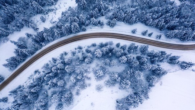 曲がった山道の航空写真ヨーロッパの曲がった山道の航空写真。冬の山の風景。雪に覆われた木々や山の斜面。ドローンビュー。ヨーロッパ。